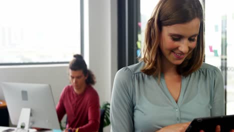 Woman-using-digital-tablet-while-colleague-working-in-background