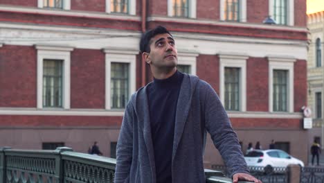 man looking up at cityscape on a bridge