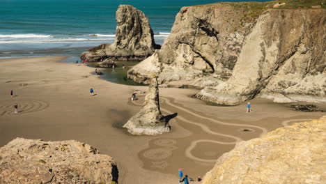 Menschen,-Die-Auf-Kunstvollen-Zeichnungen-Im-Sand-Laufen---Kreise-Im-Sand-In-Bandon,-Oregon---Hoher-Winkel,-Zeitraffer