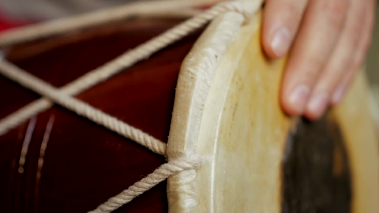Close up of hands of a man playing a drum.