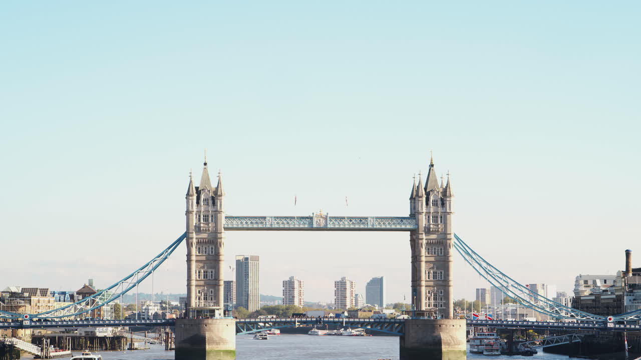 Trafik krydser Tower Bridge over Themsen på en solrig dag i London.