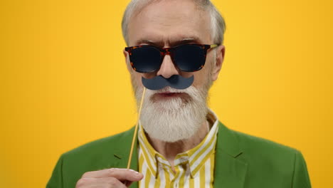 Smiling-old-man-posing-in-modern-studio.-Cheerful-guy-having-good-time-indoors.