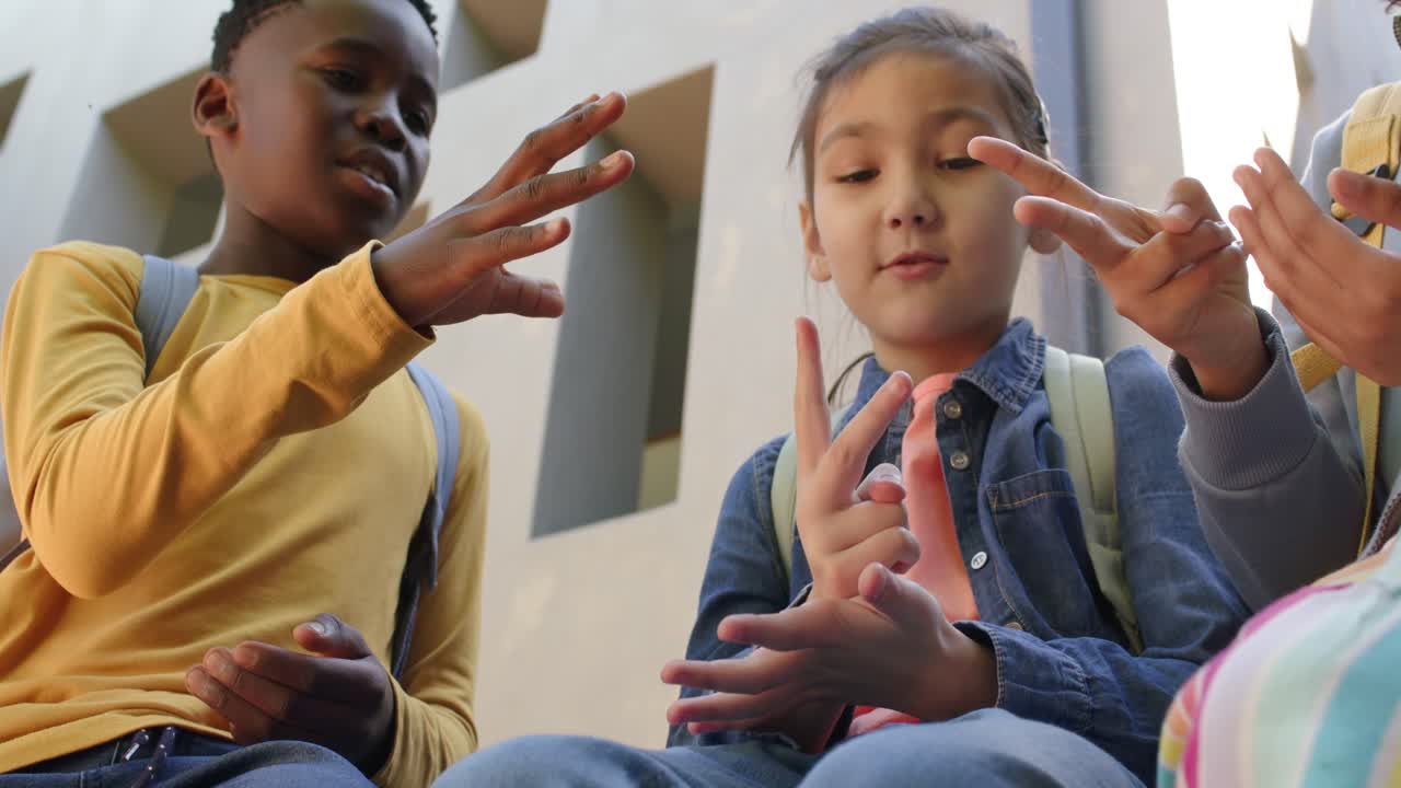African youth friends playing finger game on steps with backpacks, denim jacket, passing time