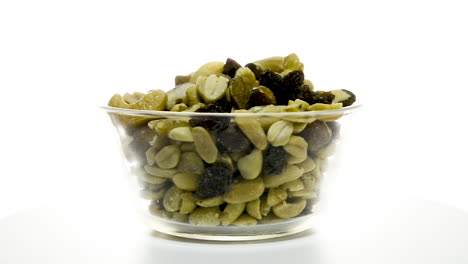 un recipiente de vidrio de nueces mixtas girando en el sentido de las agujas del reloj sobre un fondo blanco