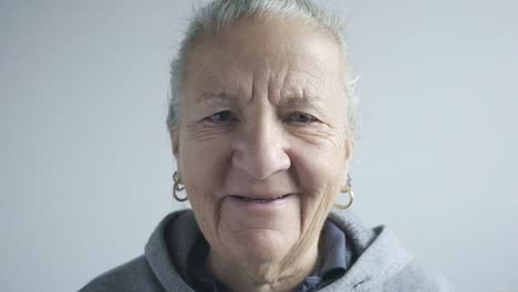 Middle-aged-woman-face-closeup,-white-hair,-blue-eyes-portrait-smile,-earrings-and-sport-wear,-studio-shot