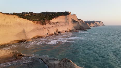 playa de acantilados con olas a la hora dorada, cabo drastis, corfú, grecia