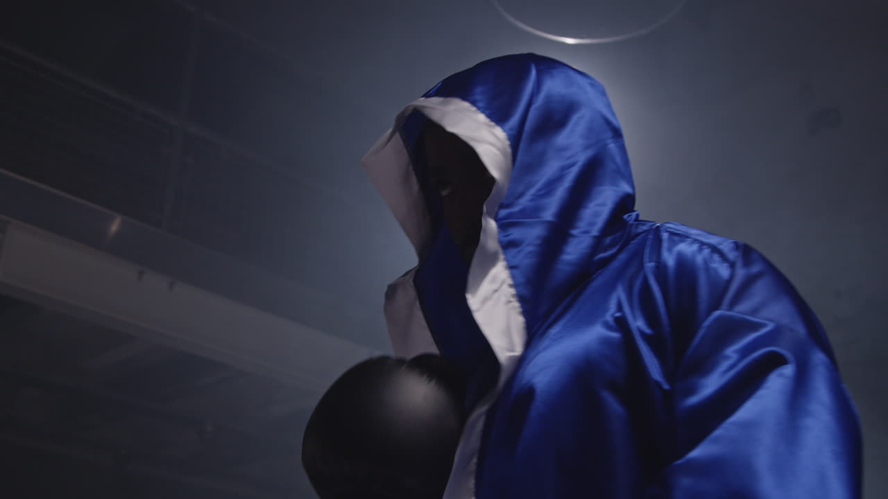 권투 경기가 시작되기 전에 장갑과 로브를 입은 권투 선수가 링에 들어갑니다.