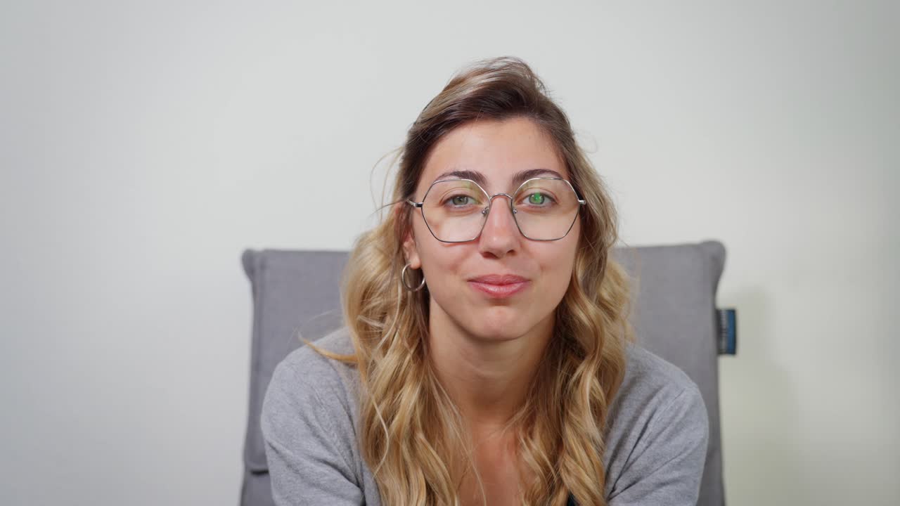 Giovane donna che sorride calorosamente mentre è seduta al chiuso in un ambiente rilassato e informale