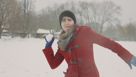 girl in winter clothes is making fun of throwing snowball in front of the camera - handheld, medium shot