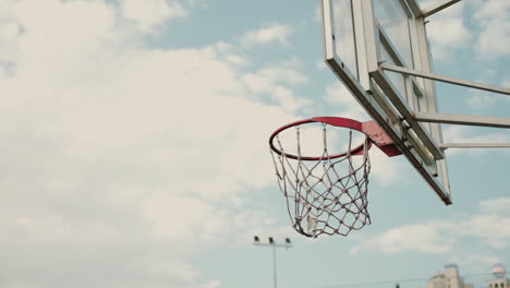 Close-Up-Of-Outdoor-Basketball-Hoop-In-A-Sunny-Day,-While-An-Unknown-Person-Throwing-Ball-Into-Basketball-Ring-Four-Times-Successfully