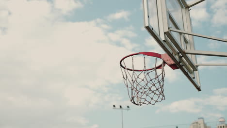 cierre del aro de baloncesto al aire libre en un día soleado, mientras que una persona desconocida lanza la pelota al aro de baloncesto cuatro veces con éxito