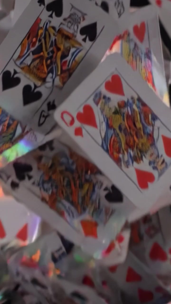 Detail hracích karet v tajemném prostředí se zaměřením na barvy srdcí a piky, zachycující podstatu hry nebo podvodu.