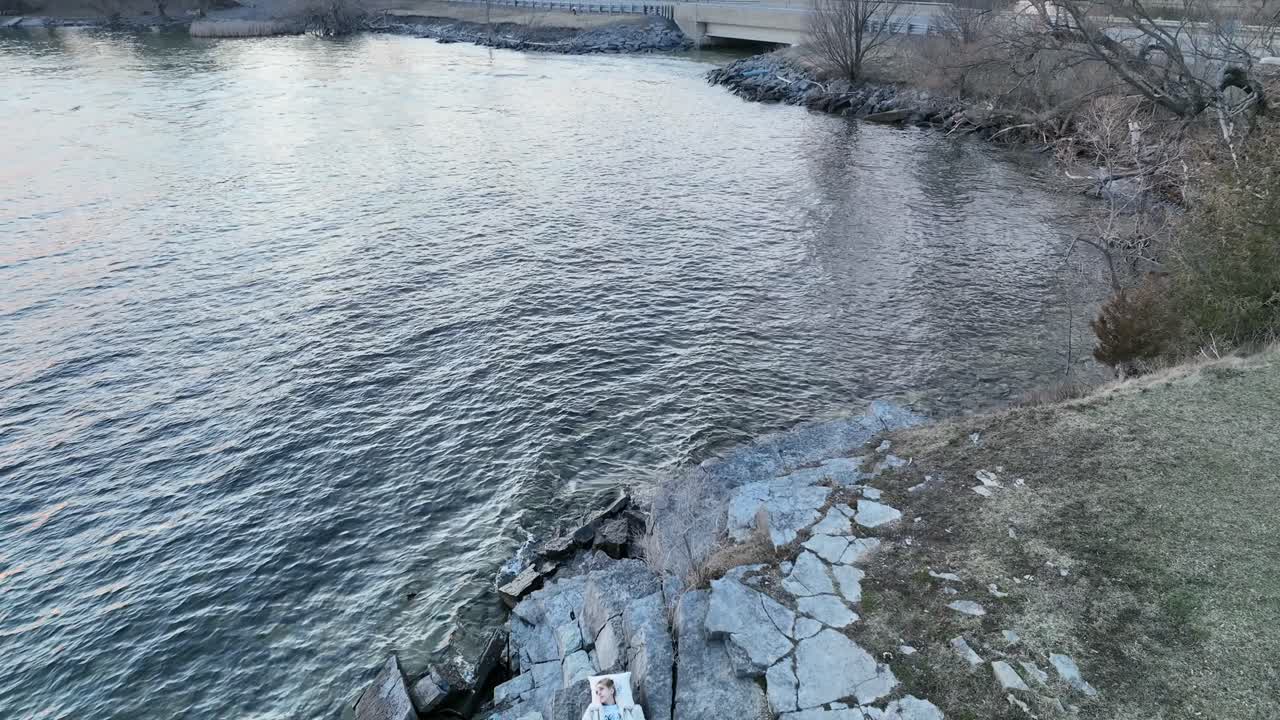 누워있는 해안가에서 봄 일몰을 즐기는 공중 젊은 여성