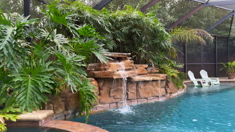 amplia vista de la piscina al aire libre con cascada y bambú en el interior del porche lanai