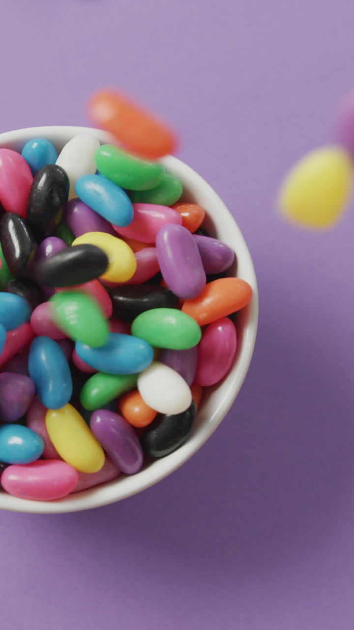 video de primer plano de dulces multicolores que caen en un cuenco sobre un fondo púrpura