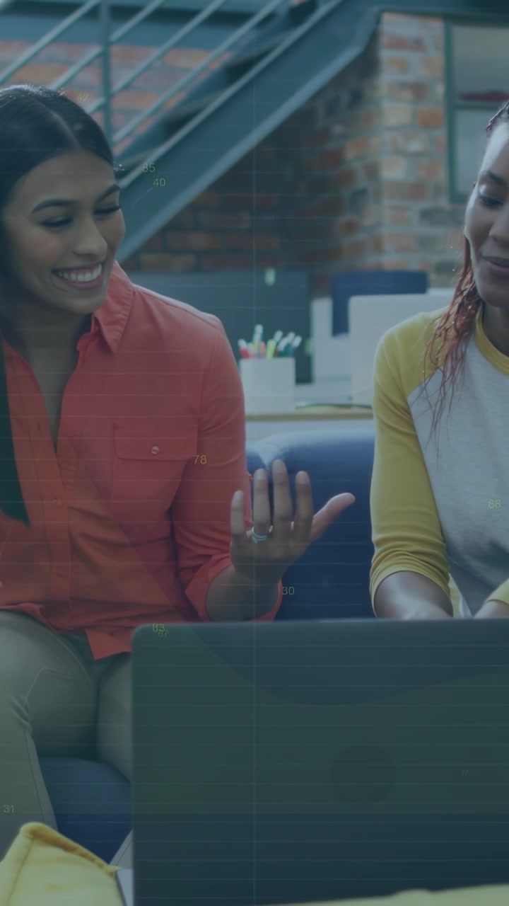Vertical video: Left woman pointing at laptop while right woman tapping, reviewing business pitch