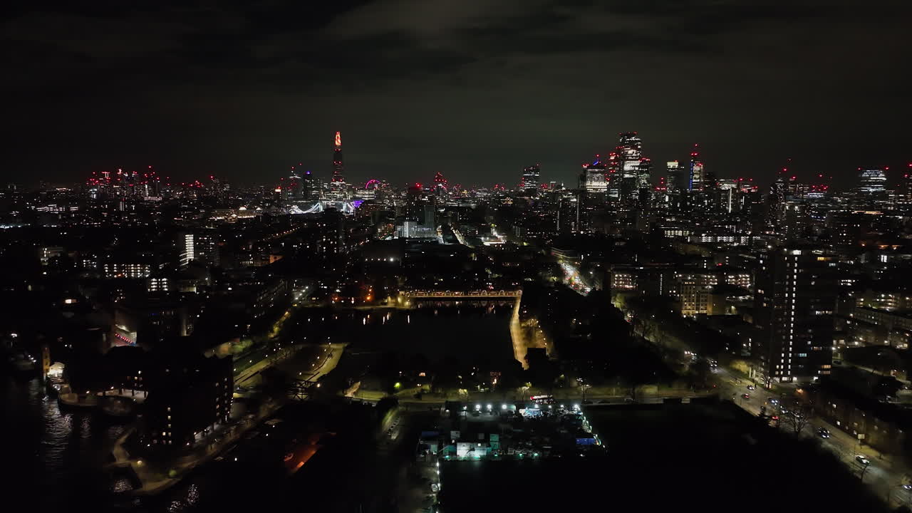 Panoramic aerial of the Shadwell basin with London skyline backdrop, night in UK