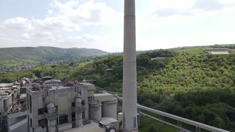 Aerial-drone-flight-ascending-upward-of-Breedon-Hope-Cement-Works-chimney-stack-in-Derbyshire-Peak-District