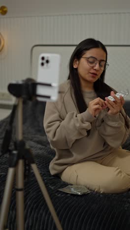 A-happy-confident-brunette-girl-in-glasses-blogs-about-medicine-tablets-and-capsules-using-her-white-smartphone-in-a-modern-apartment-at-home