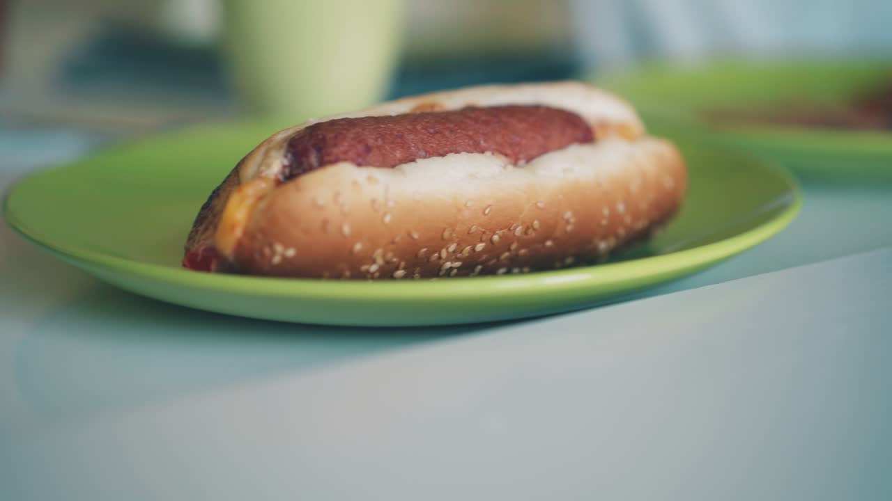 el escolar toma el perrito caliente del plato de color en el primer plano de la mesa