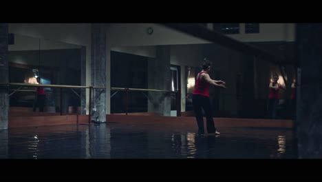 a young woman practices modern dancing and ballet in a moody room full of mirrors