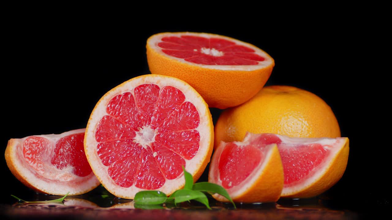 Pieces of fresh grapefruit with leaves slowly rotate.