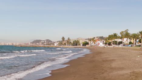 a wide angle with a pan to the left at a beach in south spain, to see the mediterranean sea and a city with mountains in the background