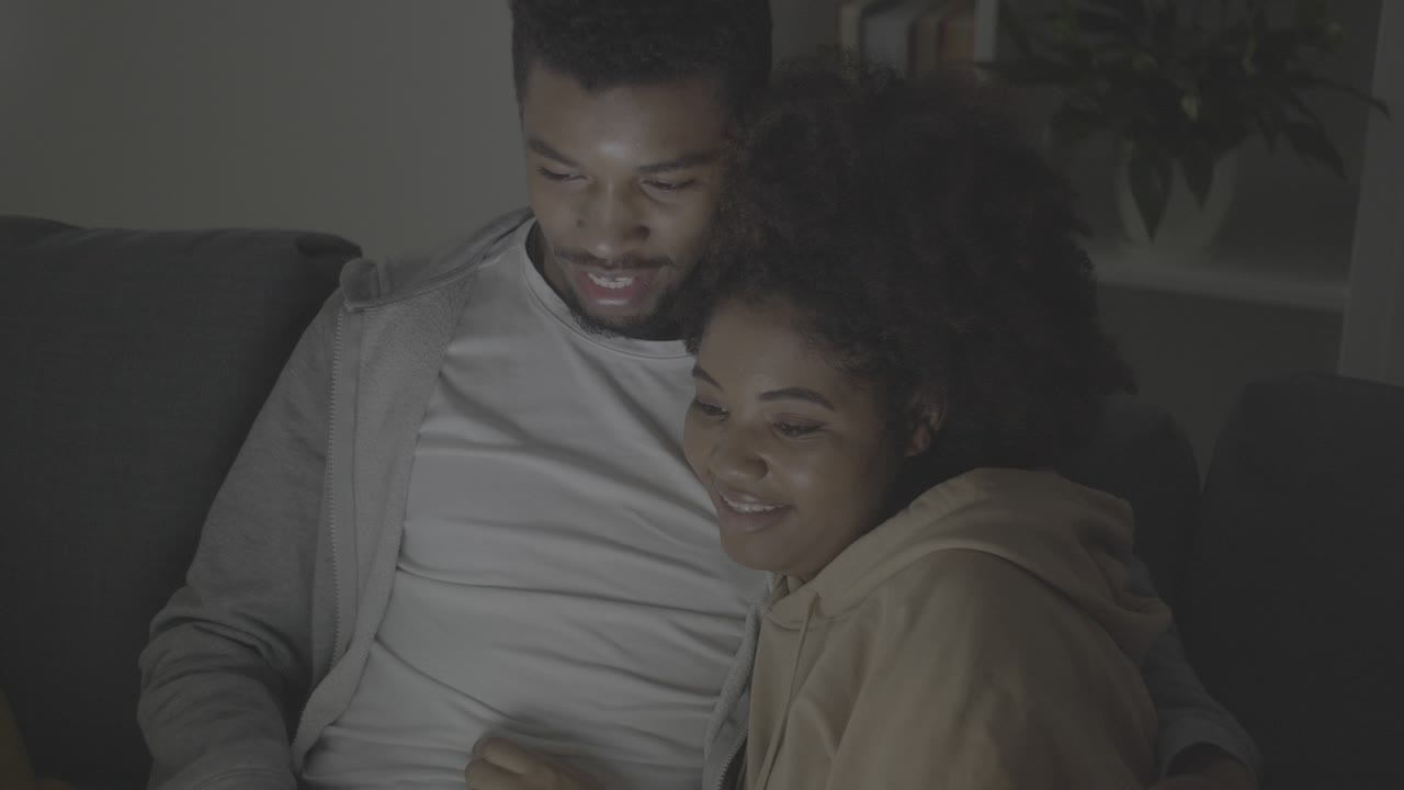 joven pareja afroamericana eligiendo una película para ver en la computadora portátil