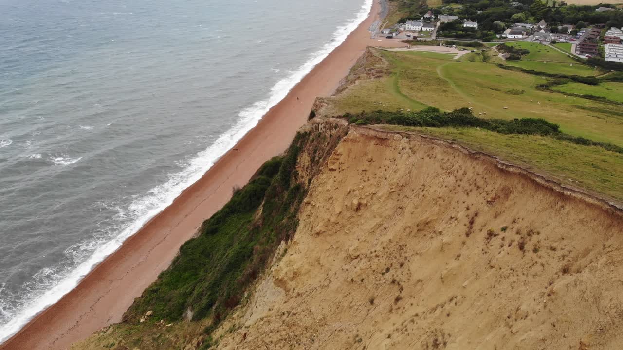 vuelo aéreo sobre grandes acantilados costeros con la costa de la playa de seatown en el fondo