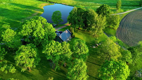 Aerial-View-Overlooking-Vacation-home-with-Lush-Green-Surroundings-of-Trees-and-Lake-in-Latvia