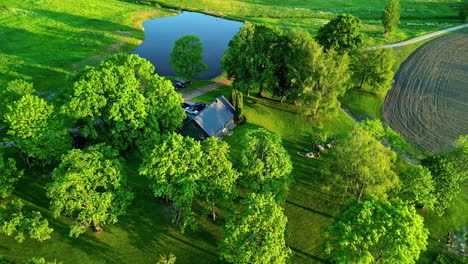 aerial view overlooking vacation home with lush green surroundings of trees and lake in latvia