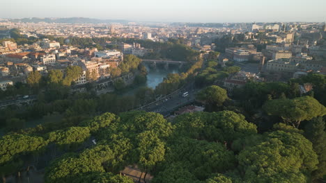 Drone-flies-above-fluffy-green-trees-to-reveal-river-and-roadway-in-Orange-Garden-Rome-Italy