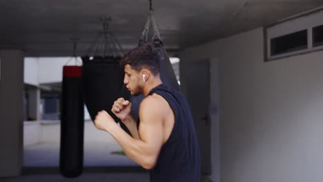 Martial-art-fighter-does-shadowboxing,-kickboxer-training-strikes-in-gym
