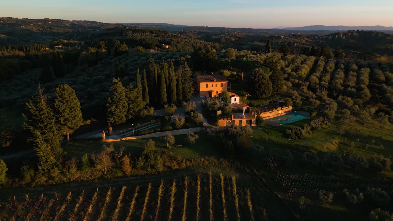 Ripresa aerea panoramica che scende verso una villa affacciata su ulivi nella campagna toscana di Certaldo.