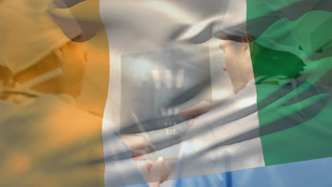 animation of flag of ivory coast, diverse surgeons discussing x-ray while walking in corridor