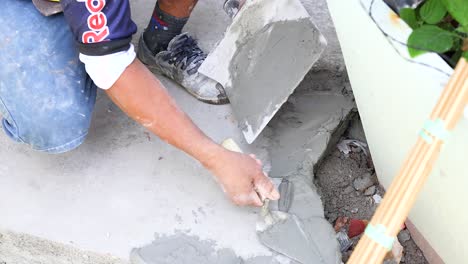a worker skillfully applies and smooths concrete on a surface in phuket, thailand, under natural daylight conditions