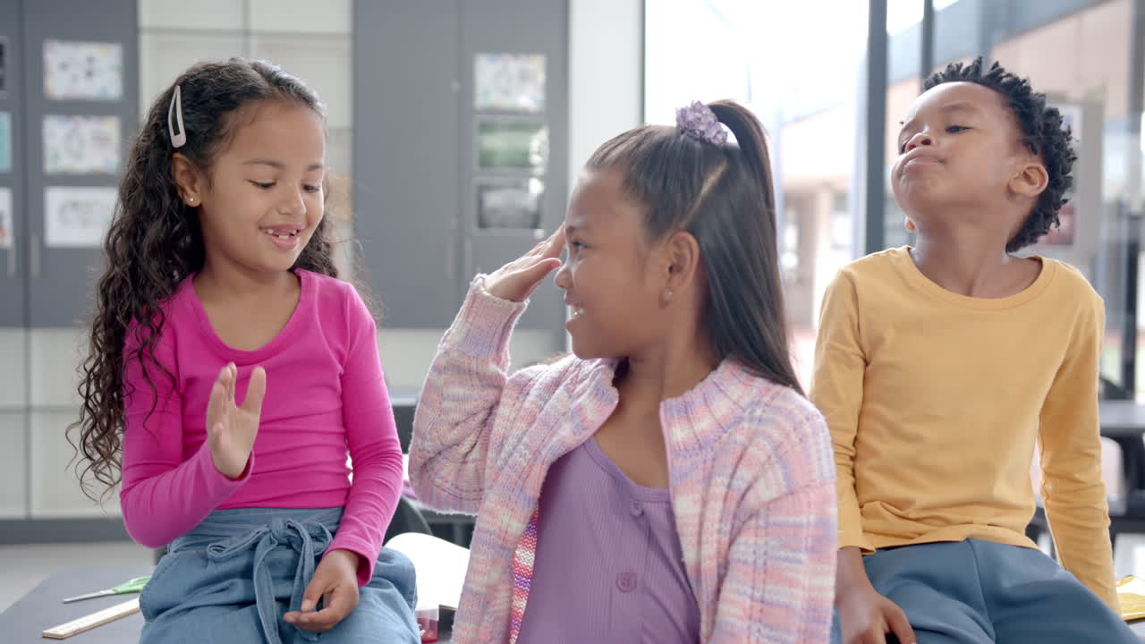 In school, three children sitting together in classroom, smiling and talking