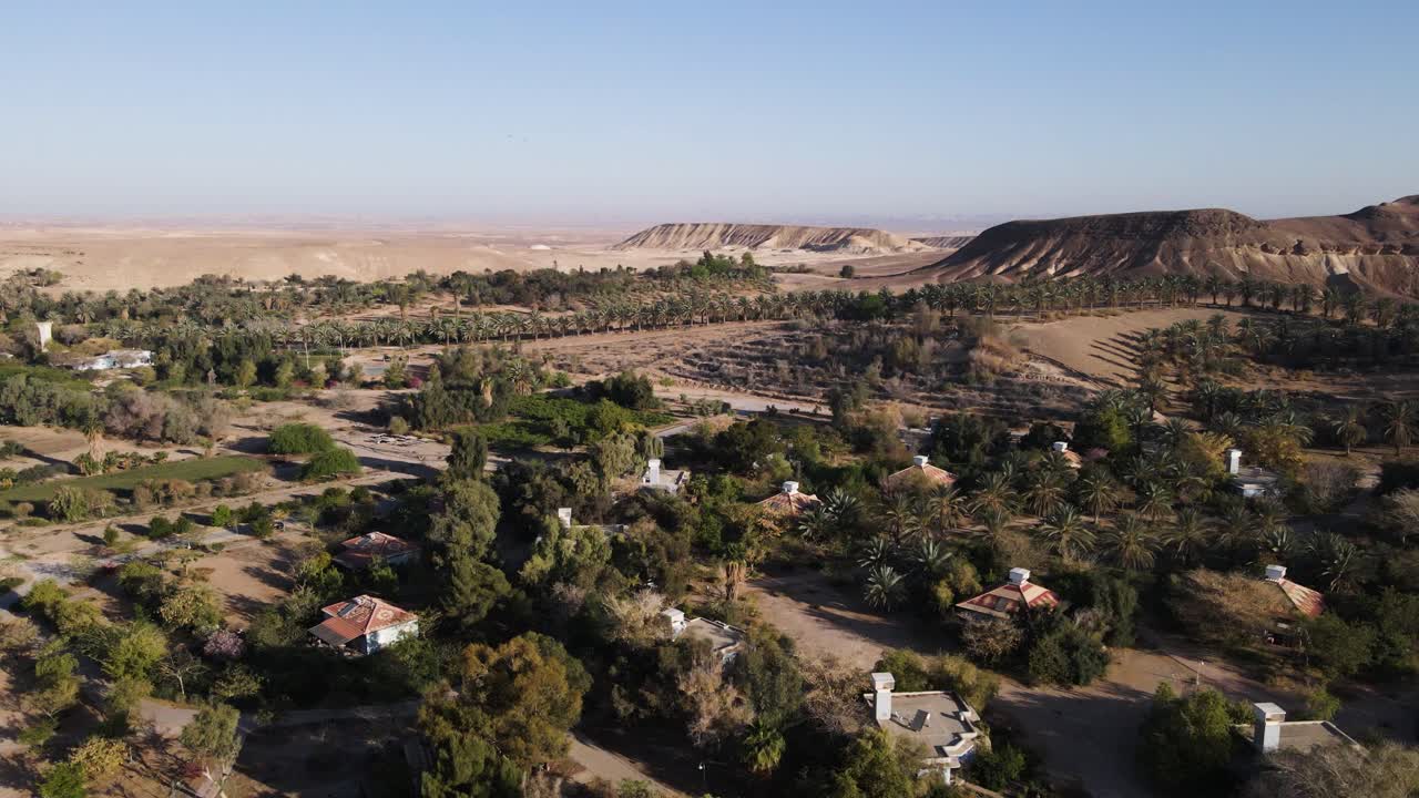 Green oasis with homes surrounded by endless desert, aerial view