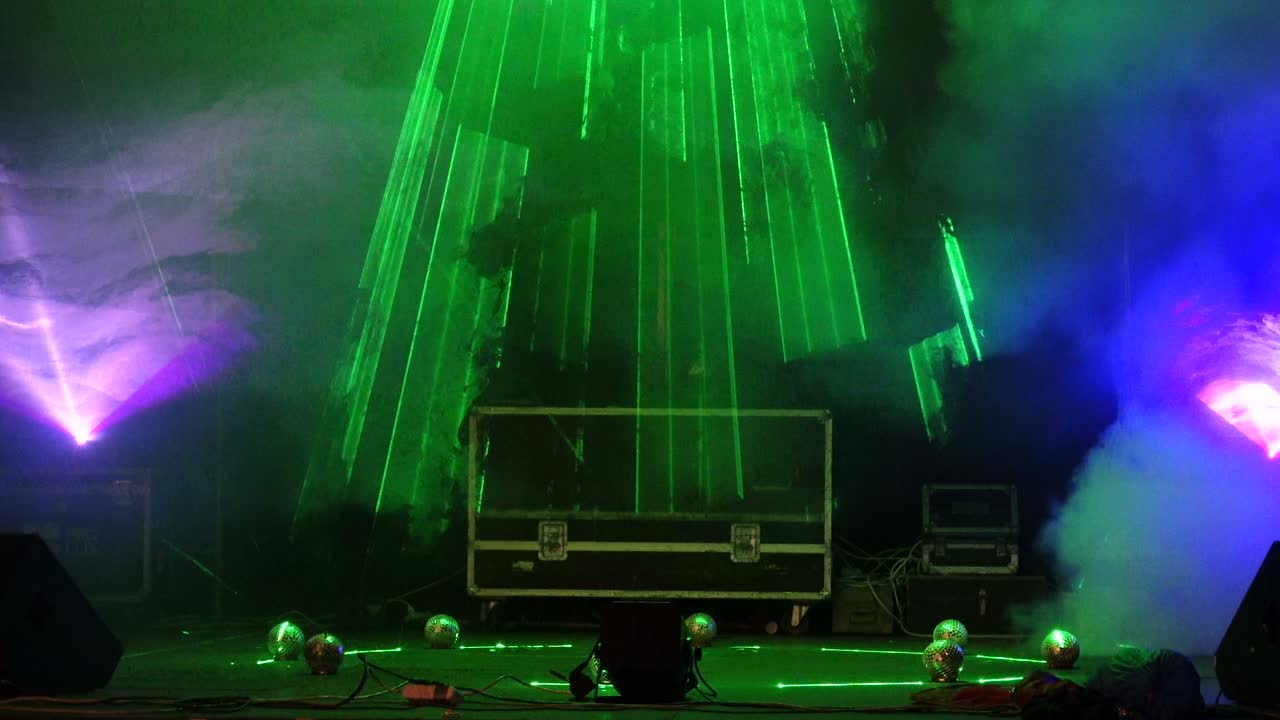 brillantes reflectores de concierto parpadeantes láseres y humo en el fondo de la escena