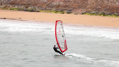 windsurfer navigating waves near sandy shore