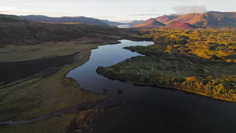 Flying-Over-Calm-Icelandic-Lake-During-Warm-Sunset-With-Beautiful-Mountain-Range-In-Background