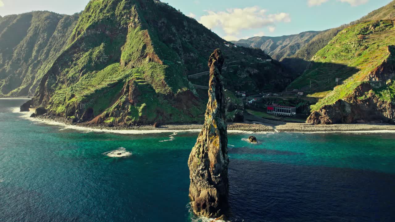 Dramatic Coastal Rock Formation and Lush Green Mountains