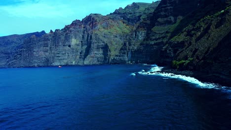 Toma-Cinematográfica-De-Agua-De-Mar-Azul-Bajo-Altas-Montañas-En-La-Isla-De-Tenerife,-España