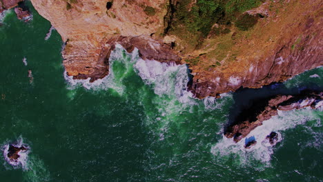 vuelo aéreo de lado sobre acantilados oceánicos escarpados, rompiendo olas, rocas