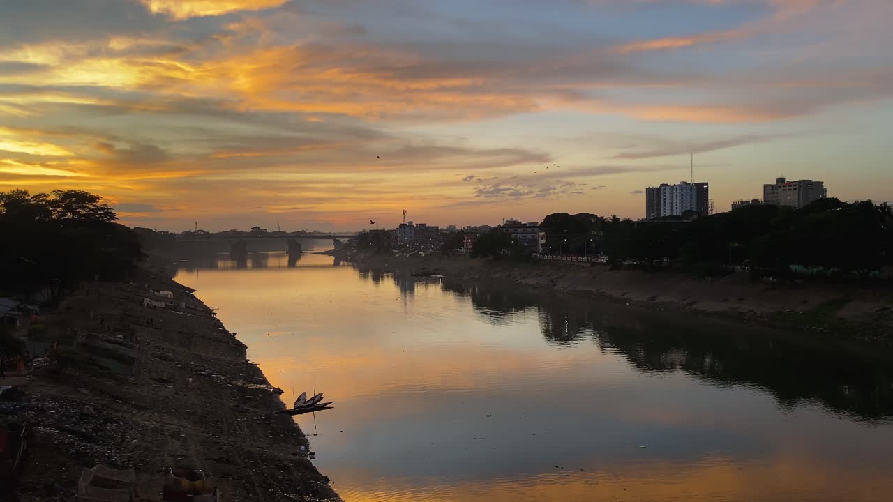 Birds flying above Surma river at dusk with dramatic sky in Sylhet, Bangladesh