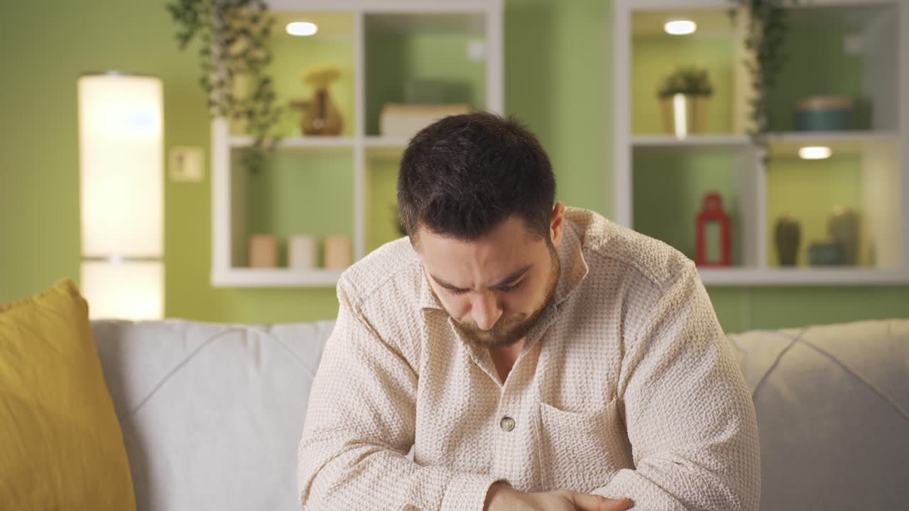hombre cansado e infeliz sentado en la sala pensando en algo.