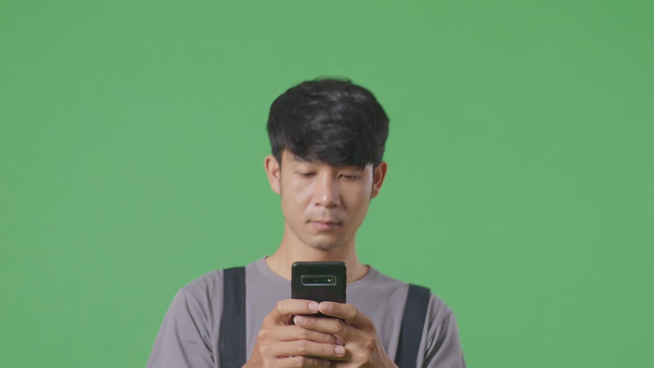녹색 화면 배경 스튜디오에서 는 동안 스마트폰을 사용하는 아시아인 노동자의 클로즈업