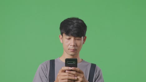 녹색 화면 배경 스튜디오에서 는 동안 스마트폰을 사용하는 아시아인 노동자의 클로즈업