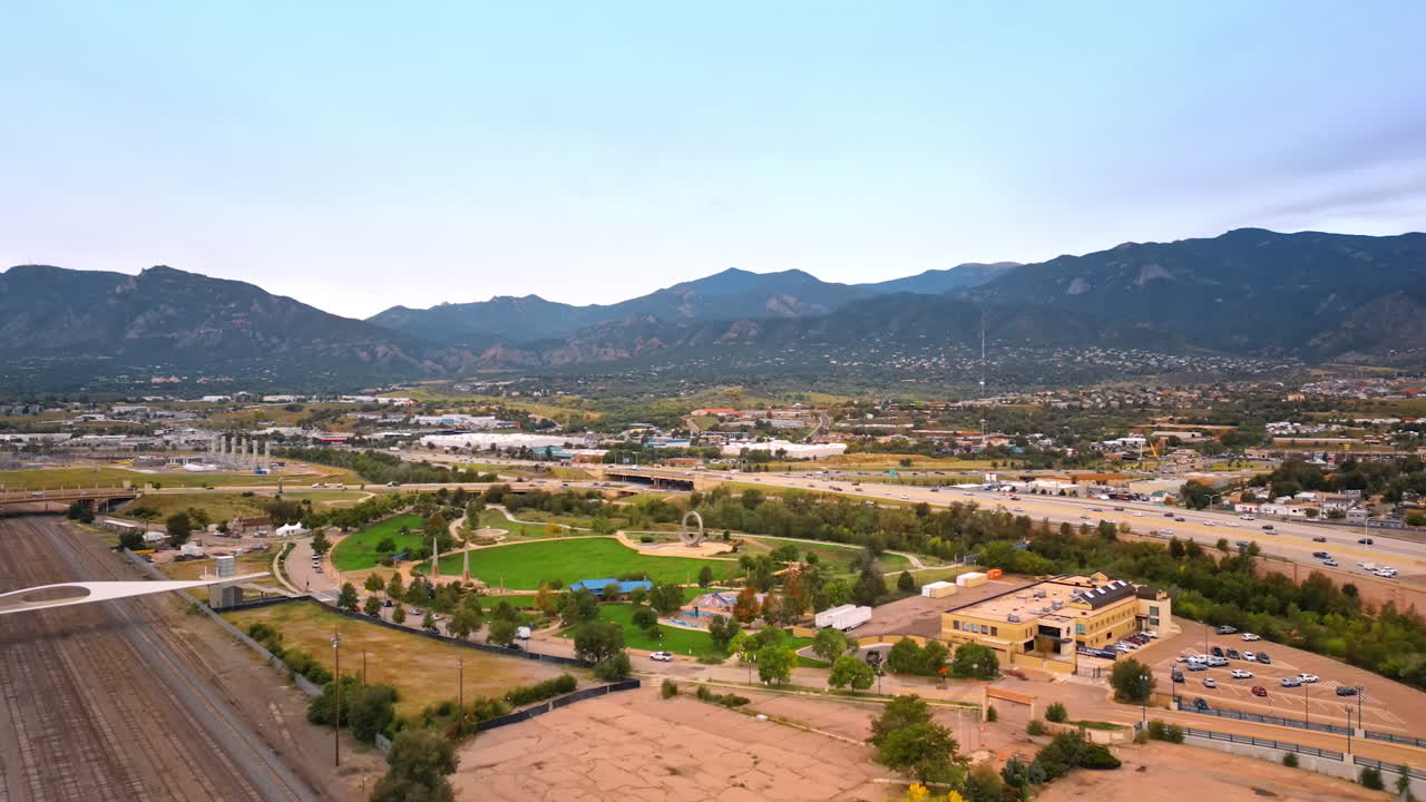 Colorado Springs, USA, 22 July 2025: Approaching the beautiful park outlined by the busy roads with multiple cars. Aerial perspective on the cityscape of Colorado Springs, Colorado, USA. Mountains at backdrop