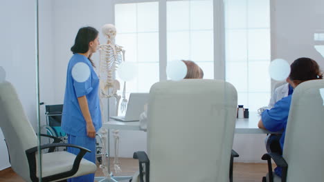 medical nurse pointing on cervical spine of human skeleton